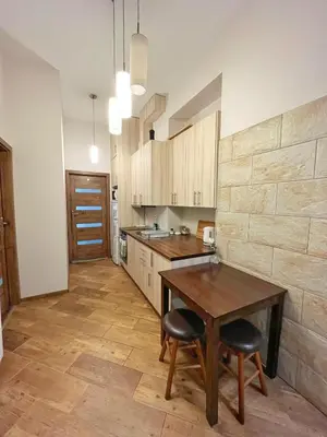 a kitchen with a wooden table and two stools at Cozy rooms in Old Town and Wawel in Kraków