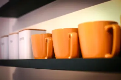 four orange coffee cups sitting on a shelf at Apartament z ogrodem w centrum Limanowej in Limanowa