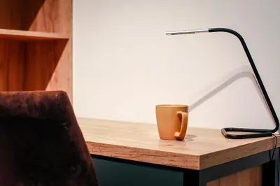 a coffee cup sitting on a desk with a lamp at Apartament z ogrodem w centrum Limanowej in Limanowa