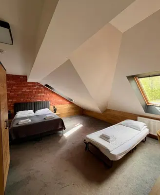 a attic bedroom with two beds and a window at Ostoja Garden in Brody