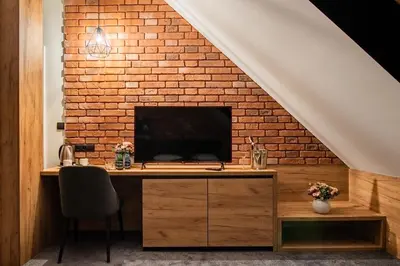 a room with a desk with a tv and a brick wall at Ostoja Garden in Brody