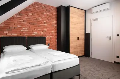 a bedroom with a large bed with a brick wall at Ostoja Garden in Brody