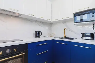 a kitchen with blue cabinets and a microwave at Apartament przy Bulwarach Wiślanych Kościuszki by Noclegi Renters in Kraków