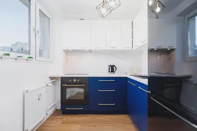 a kitchen with blue cabinets and a black oven at Apartament przy Bulwarach Wiślanych Kościuszki by Noclegi Renters in Kraków