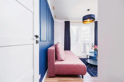 a living room with a pink chair and a table at Apartament przy Bulwarach Wiślanych Kościuszki by Noclegi Renters in Kraków