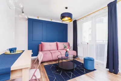 a living room with a pink couch and blue walls at Apartament przy Bulwarach Wiślanych Kościuszki by Noclegi Renters in Kraków