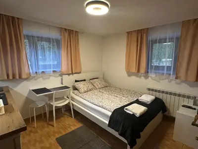 a bedroom with a bed and a table and windows at Willa Kryspinów in Kraków