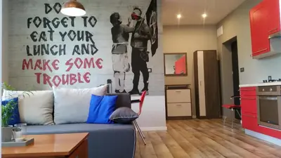 a living room with a blue couch and a kitchen at Street Art Apartment in Oświęcim