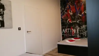 a living room with a couch and a tv on a wall at Street Art Apartment in Oświęcim