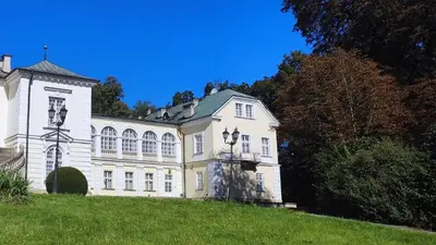 a large white house on top of a grassy hill at Pokoje Gościnne Pałac w Balicach Instytut Zootechniki PIB in Balice