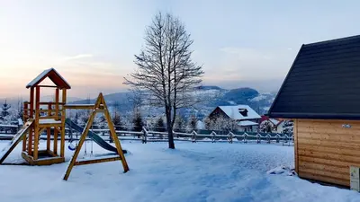 a playground in a yard covered in snow at Domki w górach Na Grapie in Stryszawa