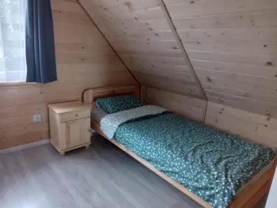 a bed in a wooden room with a wooden floor at Domki w górach Na Grapie in Stryszawa