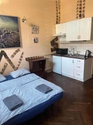 a bedroom with a bed and a kitchen with white cabinets at Adam12 in Kraków