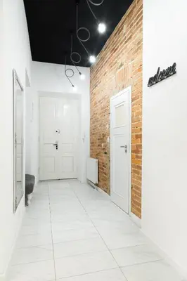 a hallway with a brick wall and two white doors at HOUSEHOST Apartment: Bogusławskiego Street in Kraków