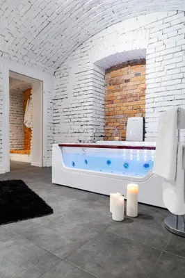 a bathroom with a tub in a brick wall at HOUSEHOST Apartment: Bogusławskiego Street in Kraków