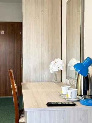 a table with a remote control and flowers on it at Hotel Arkadia in Klecza Górna