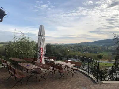 a patio with tables and an umbrella on a balcony at Hotel Arkadia in Klecza Górna