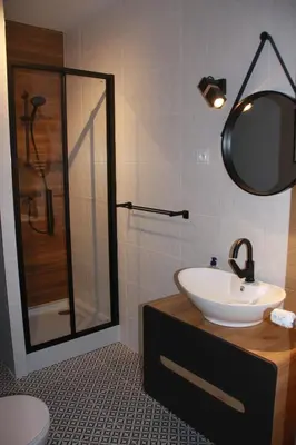 a bathroom with a sink and a shower with a mirror at Niko Apartments 1 in Kraków