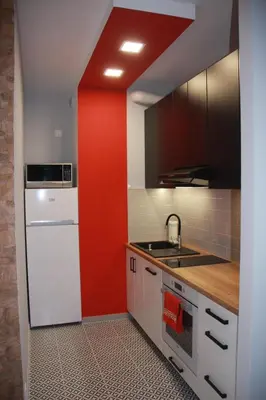 a kitchen with a red wall and a white refrigerator at Niko Apartments 1 in Kraków