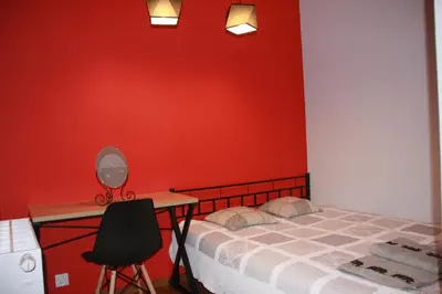a bedroom with a red wall and a bed and a desk at Niko Apartments 1 in Kraków