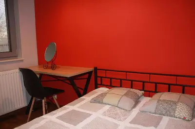 a red bedroom with a bed and a desk at Niko Apartments 1 in Kraków