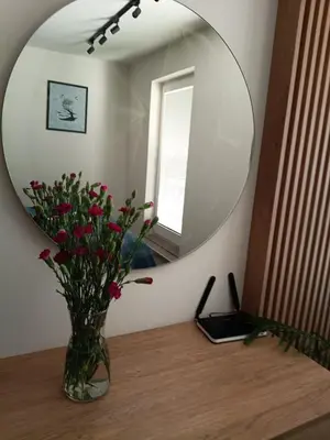 a vase with flowers on a table in front of a mirror at Apartament Lena Stare Miasto in Kraków