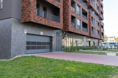 a large brick building with a garage door and grass at Comfort, prestige, best location Romanowicza 1 in Kraków