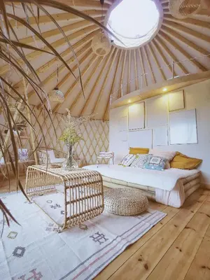 a room with two beds and a table and a ceiling at LushHills - Nowoczesna Jurta in Regulice