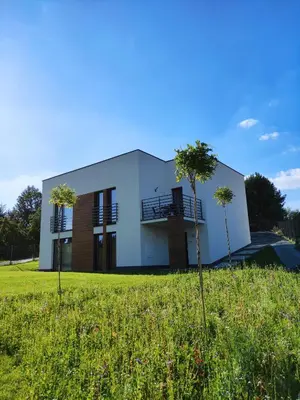 a white house with two trees in a field at Trzy Małe Drzewka in Wielka Wieś