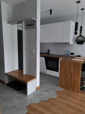 a kitchen with white cabinets and a wooden table at APARTAMENT DĄBSKA 24 TAURON ARENA in Kraków