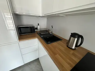 a small kitchen with white cabinets and a microwave at APARTAMENT DĄBSKA 24 TAURON ARENA in Kraków