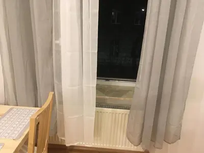 a window with white curtains next to a radiator at Pure Apartments in Kraków