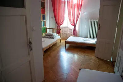 a room with two beds and a window with red curtains at Trzy Kafki Private Rooms in Kraków