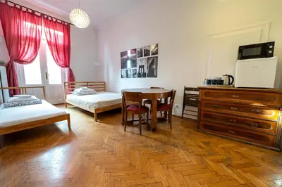 a room with two beds and a table with a desk at Trzy Kafki Private Rooms in Kraków