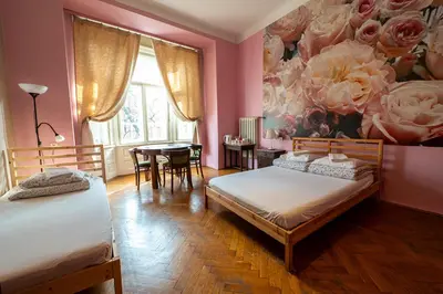 a bedroom with two beds and a table and a painting of roses at Trzy Kafki Private Rooms in Kraków