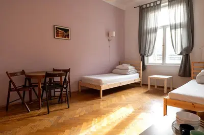 a room with a table and a bed and a table and chairs at Trzy Kafki Private Rooms in Kraków