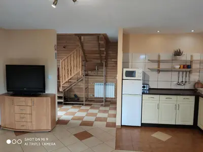 a kitchen with a refrigerator and a tv in a room at Domek u Lucy in Rabka