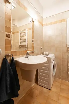 a bathroom with a sink and a washing machine at Negroni Apartments Stare Miasto in Kraków