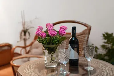 a table with a bottle of wine and a vase of pink flowers at Negroni Apartments Stare Miasto in Kraków
