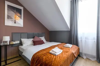 a bedroom with a bed with an orange blanket at Friendhouse Residence in Kraków