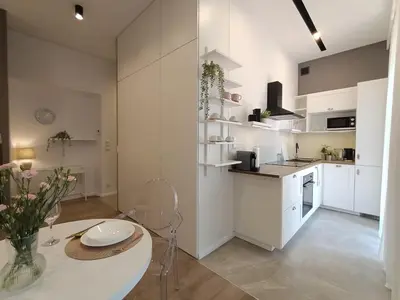 a kitchen with white cabinets and a table in a room at MyFive Apartments Kraków in Kraków