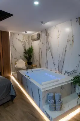 a bath tub in a room with a marble wall at Jacuzzi Apartment Main Square in Kraków