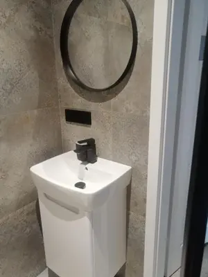 a bathroom with a white sink and a mirror at Prokocim Apartments in Kraków