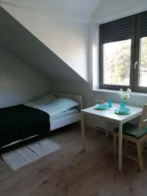 a bedroom with a bed and a table and a bed and a window at Prokocim Apartments in Kraków