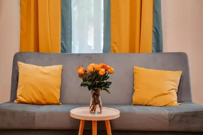 a vase of orange flowers on a table in front of a couch at ALPARI apartments in Kraków
