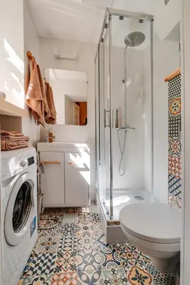 a bathroom with a shower toilet and a washing machine at ALPARI apartments in Kraków