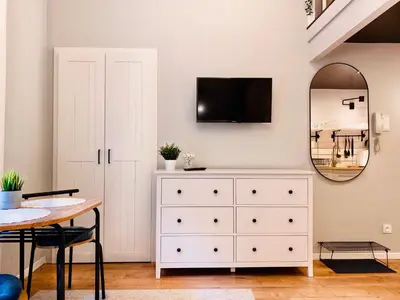 a dining room with a white dresser and a mirror at Cozy Studio with mezzanine - Old Town, Kazimierz in Kraków