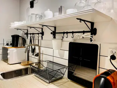 a kitchen with a sink and a shelf with utensils at Cozy Studio with mezzanine - Old Town, Kazimierz in Kraków