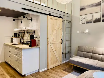 a kitchen with a sliding barn door and a couch at Cozy Studio with mezzanine - Old Town, Kazimierz in Kraków