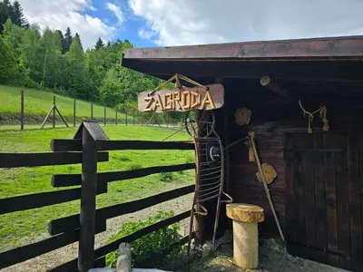 a sign on a building next to a fence at Osada Mała Kozówka in Myślenice